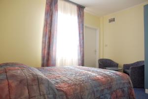 a bedroom with a bed and a window and chairs at Garni Hotel Siesta in Nova Gorica