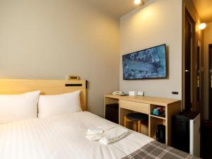 a hotel room with a bed with a desk and a tv at Hotel La Foresta By Rigna in Fukuoka