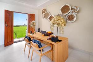 a room with a wooden desk with chairs and a window at Aeera Villa Canggu by Ini Vie Hospitality in Canggu