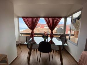 a dining room table with chairs and a large window at Departamento con vista al mar in Viña del Mar