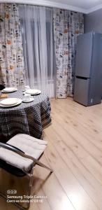 Un comedor con una mesa y un refrigerador. en Алматушечка, en Almaty