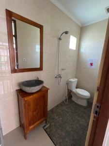 La salle de bains est pourvue d'un lavabo, de toilettes et d'un miroir. dans l'établissement Sujana Homestay, à Ubud