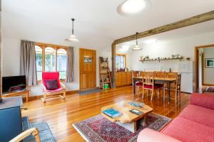 sala de estar con sofá rojo y mesa en Herons Rise Vineyard Accommodation, en Kettering