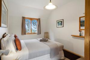 1 dormitorio con cama blanca y ventana en Herons Rise Vineyard Accommodation, en Kettering