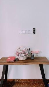 a wooden table with flowers on a white wall at Kamilia Homestay KB City Centre in Kota Bharu