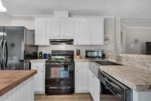 a kitchen with white cabinets and stainless steel appliances at Beachin' Fun in Navarre