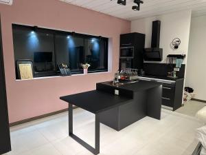 a kitchen with a black table and a pink wall at La KAZA-De-LINE in Saint-Joseph
