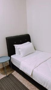 Kamilia Homestay KB City Centre في كوتا بْهارو: سرير أبيض مع اللوح الأمامي الأسود وطاولة