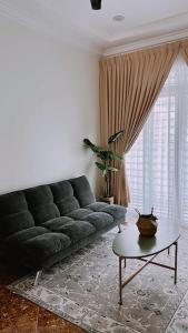 a living room with a black couch and a table at Kamilia Homestay KB City Centre in Kota Bharu