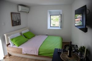 a bedroom with a bed with green pillows and a table at Apartment Dapcevic Skadar lake in Vranjina