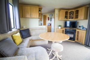 una pequeña sala de estar con mesa y sofá en Lovely 8 Berth Caravan At Naze Marine Holiday Park Ref 17012p, en Walton-on-the-Naze