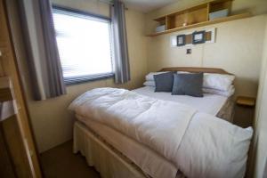 a bedroom with a large bed with a window at Lovely 8 Berth Caravan At Naze Marine Holiday Park Ref 17012p in Walton-on-the-Naze