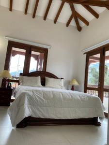 1 dormitorio con 1 cama grande con sábanas blancas y ventanas en CASA BELLA, en Villa de Leyva
