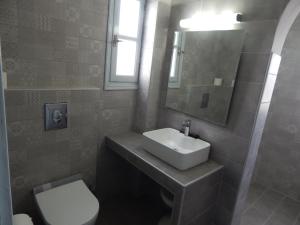 bagno con lavandino, servizi igienici e specchio di Petra Nera a Perissa