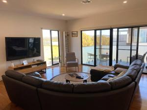 sala de estar con sofá de cuero y TV en Sanary a modern beach home in Martha Cove ideally located for the Harry Potter Hidden forest experience en Safety Beach