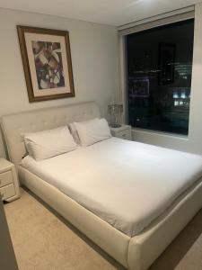 a white bed in a bedroom with a window at Embassy 812 free parking in Adelaide +5 photos