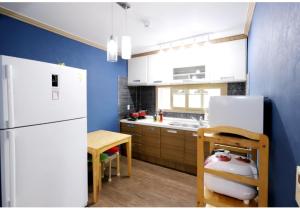 Una cocina con un refrigerador blanco y una mesa. en Jeju Olle House, en Jeju