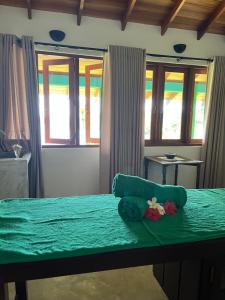 a room with a green bed with windows at Atulya Lake View - Resort and Spa in Mirissa