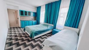 ein Schlafzimmer mit blauen Vorhängen und 2 Betten darin in der Unterkunft Surf Dacha Guest House in Karakol