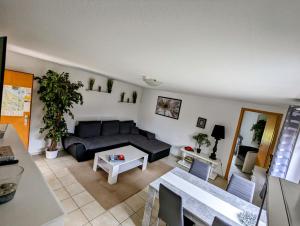 ein Wohnzimmer mit einem schwarzen Sofa und einem Tisch in der Unterkunft FeWo24-Prasdorf in Prasdorf