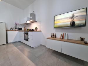 een keuken met witte kasten en een tv aan de muur bij Best House Assemini in Assemini