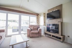 a living room with a television and a couch and a chair at Beautiful 6 Berth Caravan By The Beach In Suffolk Ref 40076nd in Lowestoft