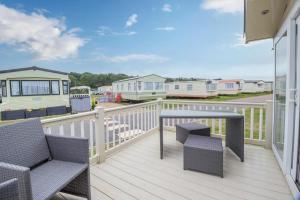 a balcony with two chairs and a table on a deck at Beautiful 6 Berth Caravan By The Beach In Suffolk Ref 40076nd in Lowestoft