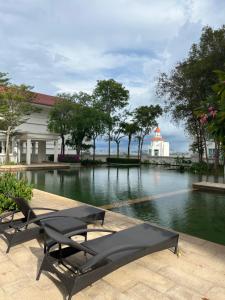a swimming pool with two benches and a building at 2Beds Seaview Straits Quay comes with Carpark and Hothub in Bagan Jermal