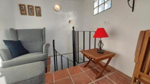 a living room with a chair and a table with a lamp at Casa TRIGO in Cómpeta