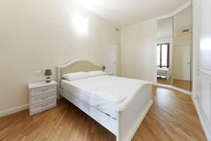 Dormitorio blanco con cama blanca y espejo en Elegant Apartment, en Milán