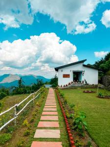 a pathway in front of a white building at Shivoham Himalayan Resort in Almora