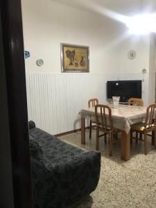 un soggiorno con tavolo, sedie e TV di Apartment La Paloma in Alghero centre ad Alghero