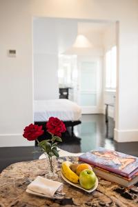 une table avec une assiette de fruits et un vase de fleurs dans l'établissement CIRCA 1936 Art Hotel, à Corowa