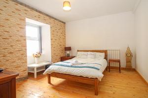 a bedroom with a bed and a brick wall at Deluxe Apartment in Lanark
