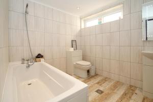 ein weißes Bad mit einer Badewanne und einem WC in der Unterkunft Deluxe Apartment in Lanark