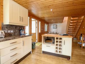 cocina con armarios blancos y techo de madera en Harmony House en Great Yarmouth