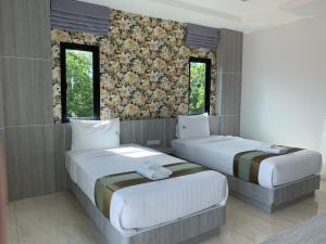 two beds in a room with two windows at Lailaresidence in Yala