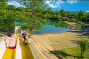 dos personas en una montaña rusa junto a un lago en Camping Domaine des Iscles, en La Roque-d'Anthéron