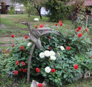 a bird statue in a garden of flowers at Magdi vendégház in Šupljak