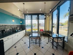 a kitchen with a table and some chairs and windows at Casa Blanca Hotel & Suites Orange SR-55 Freeway, Near Honda Center, Chapman University, Disneyland in Orange