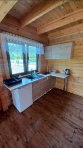 a kitchen in a log cabin with a sink and a window at Słoneczne Zacisze in Smołdziński Las