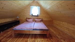 ein Schlafzimmer mit einem Bett in einer Holzhütte in der Unterkunft Słoneczne Zacisze in Smołdziński Las