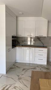 a kitchen with white cabinets and a marble floor at Apartman Žepče in Žepče