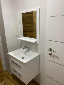 a white bathroom with a sink and a mirror at Apartman Žepče in Žepče