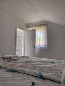 a large bed in a white room with a window at Apartman Žepče in Žepče