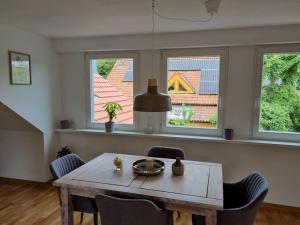 una sala da pranzo con tavolo e sedie e due finestre di Schöne naturnahe und ruhige Wohnung a Telgte