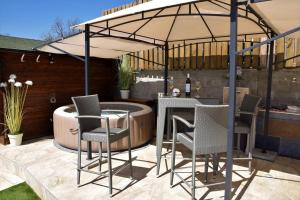 een patio met een tafel en stoelen onder een parasol bij Luxury Flat with Heated Pool & Jacuzzi in Rijeka