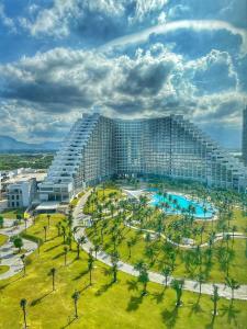 a large building with a pool and palm trees at The Arena Cam Ranh Beach Front in Cam Ranh