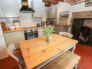 a kitchen with a wooden table with flowers on it at Arklehurst in Low Eskcleth