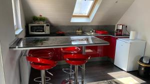 cocina con taburetes rojos y encimera con microondas en Chalet l Écrin Vert, en Plaine